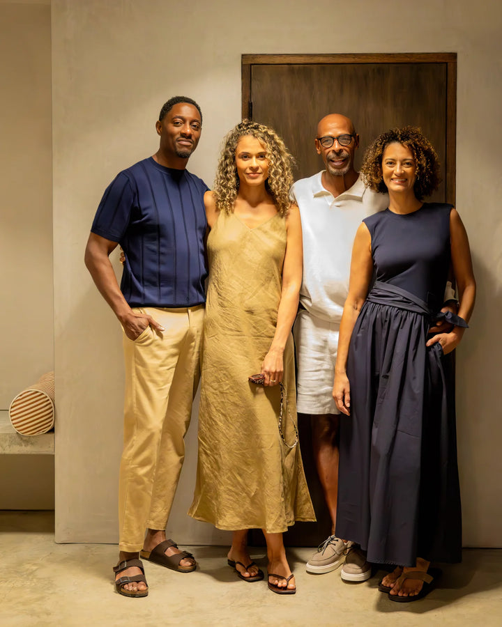 Four people posing together in a room with a wooden door.