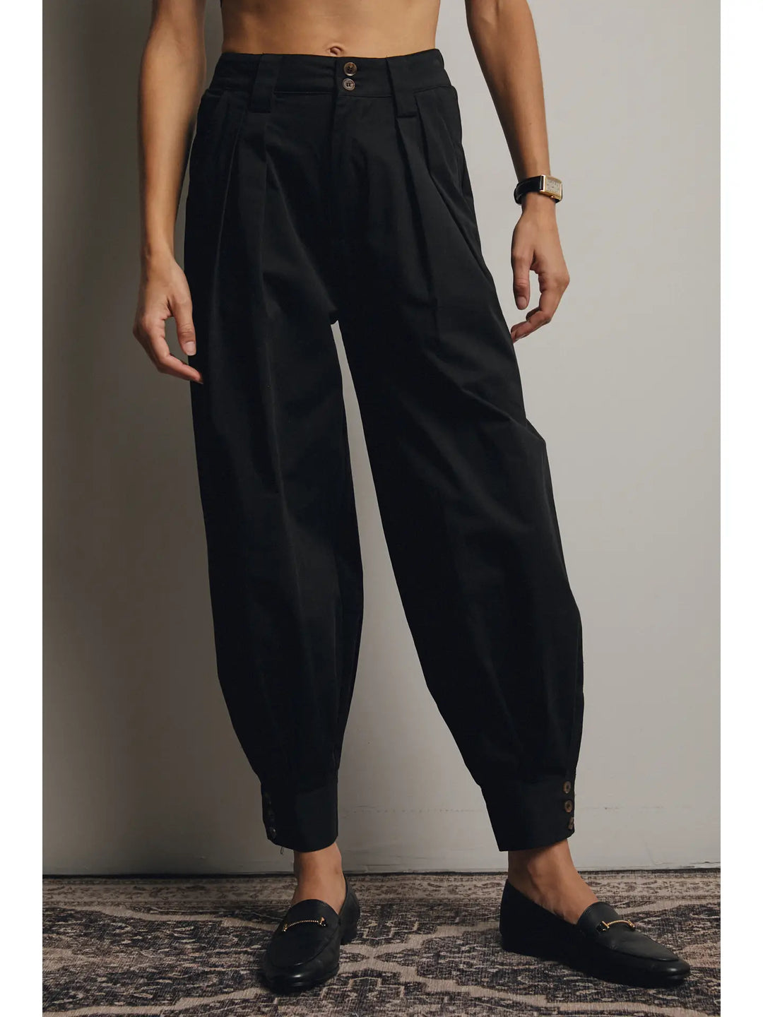 Person wearing black high-waisted pants against a plain background