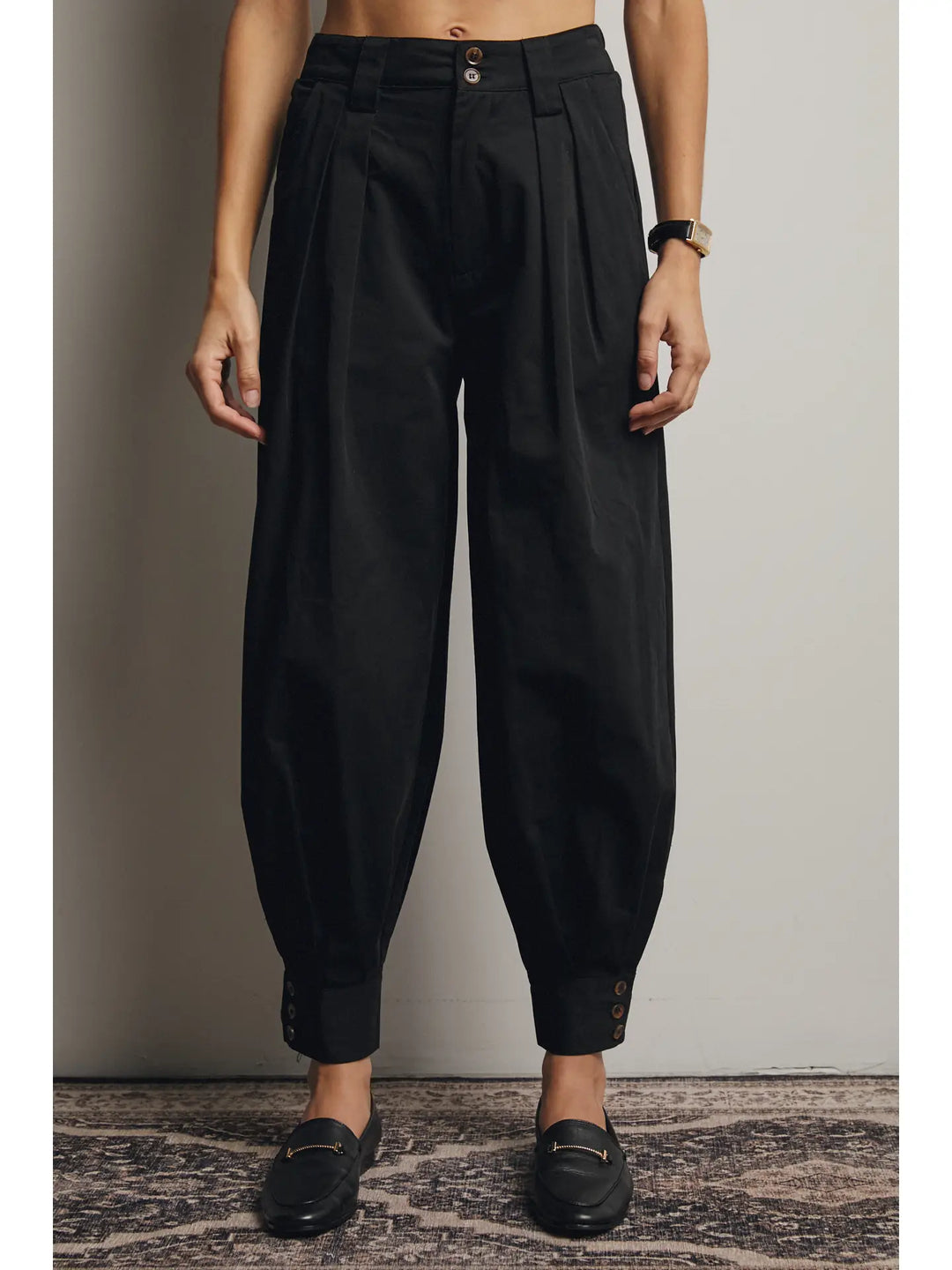 Person wearing black high-waisted pants against a plain background