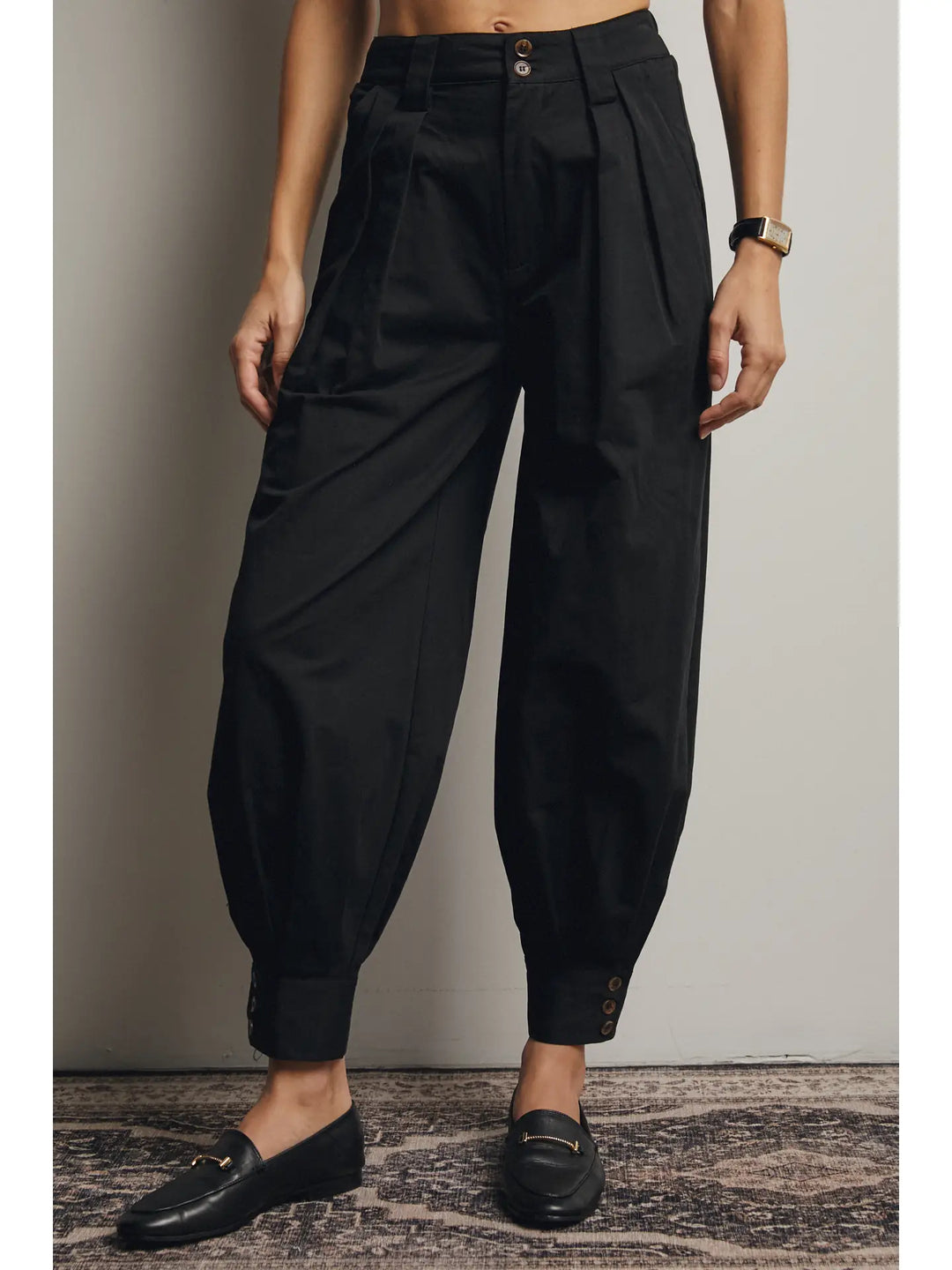 Person wearing black high-waisted pants with a plain background