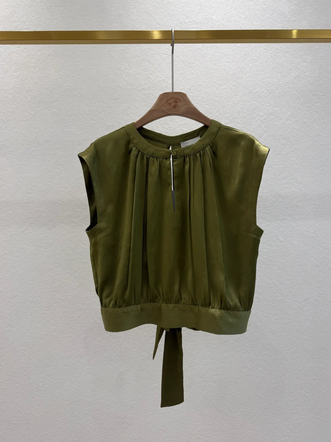 Green sleeveless top on a hanger against a white background