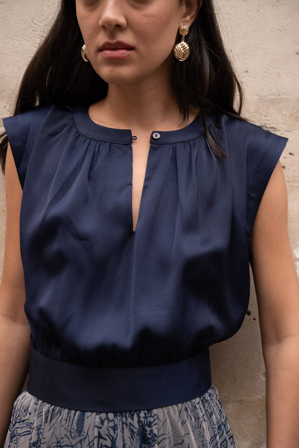 Woman wearing a navy blue sleeveless top against a neutral background