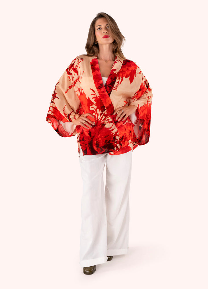 Woman wearing a red and beige floral kimono-style garment on a white background