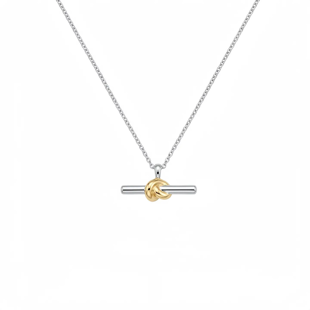 A silver-toned chain necklace with a horizontal bar pendant featuring a gold-toned knotted accent in the center, shown on a plain white background.