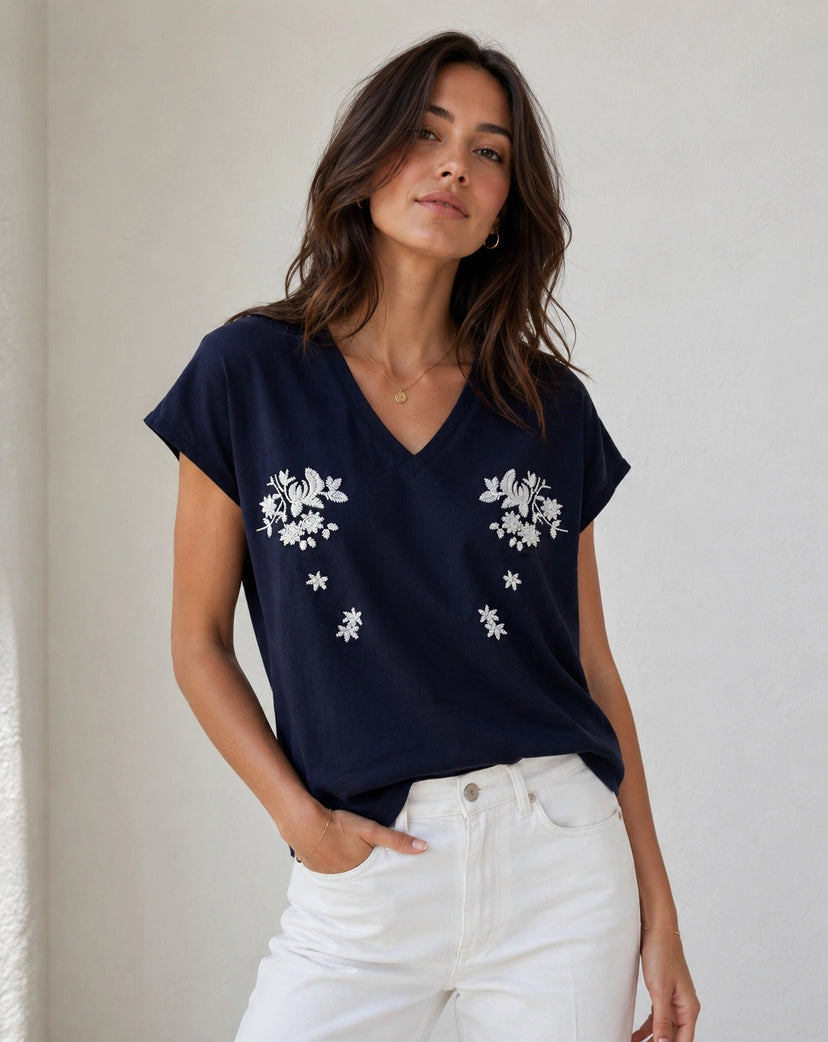 Woman wearing a navy blue t-shirt with white floral patterns against a plain background