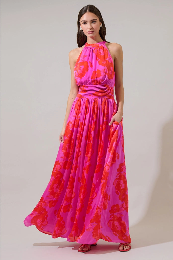 Woman wearing a pink and red floral dress against a plain background