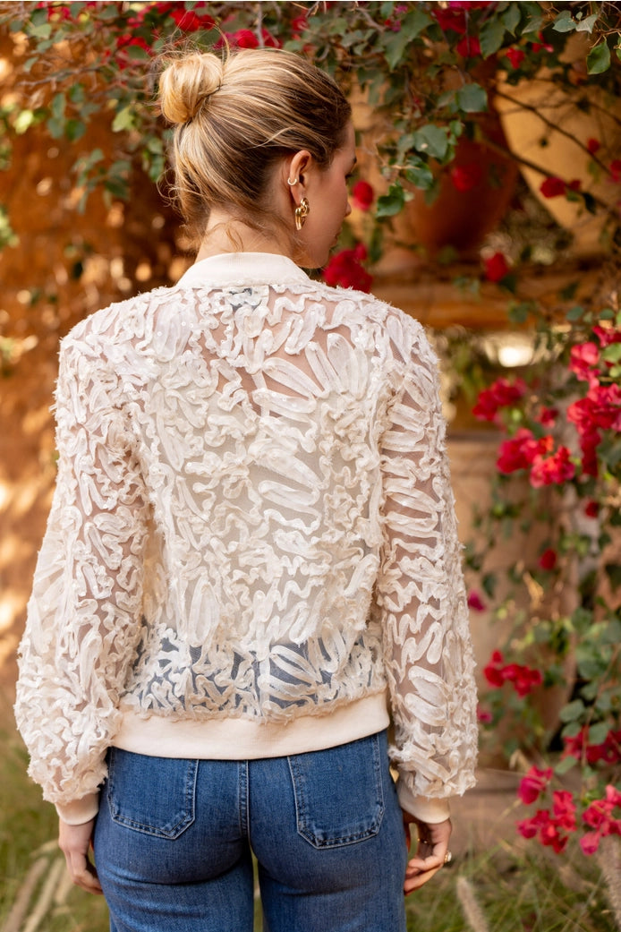 Woman wearing a lace jacket with a floral background