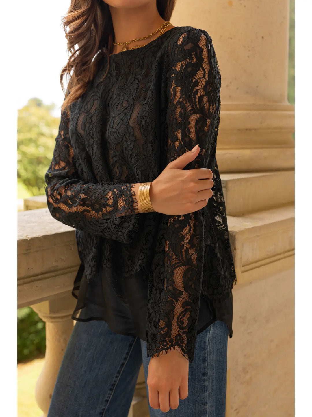 Person wearing a black lace top and jeans standing outdoors.