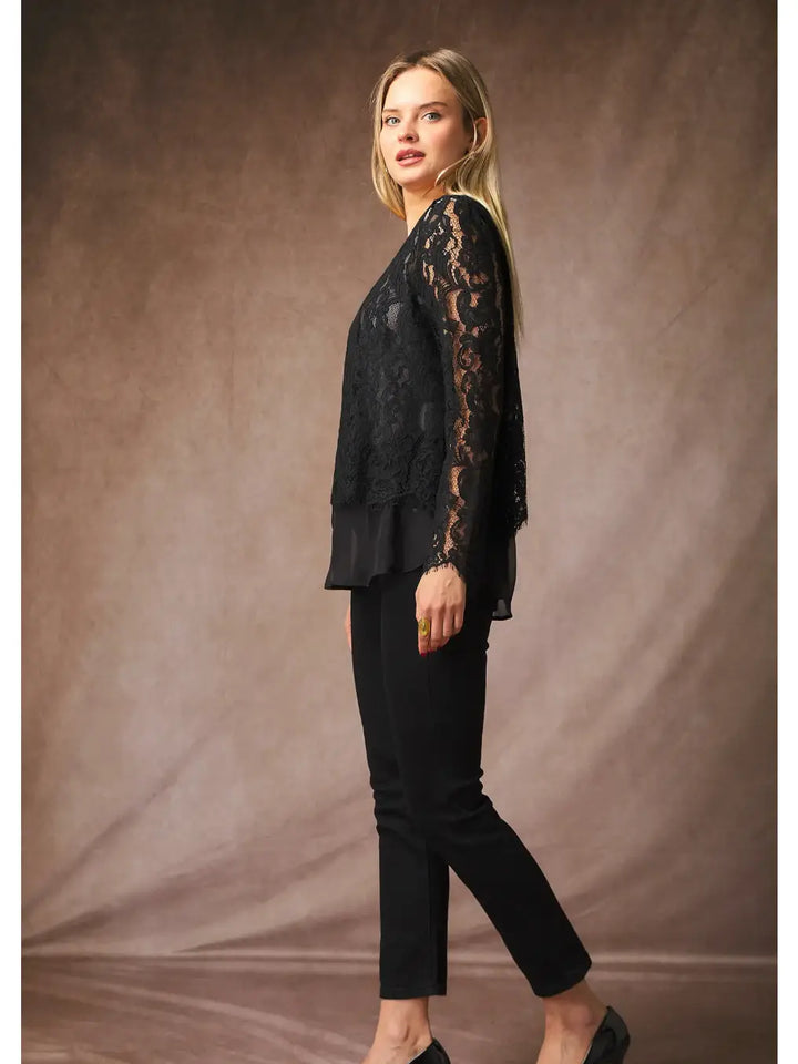 Woman wearing a black lace top and black pants against a brown background