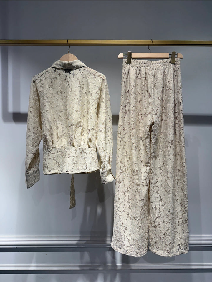 Light-colored lace outfit with jacket and pants on hangers against a neutral background