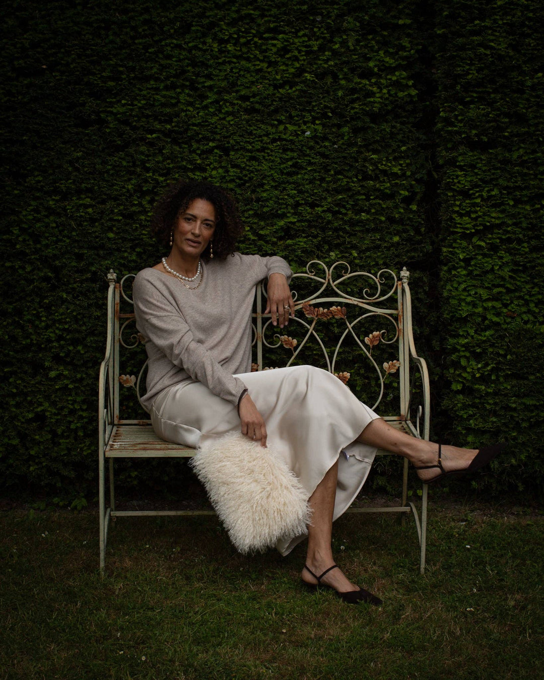 Woman sitting on a white bench against a dark green wall