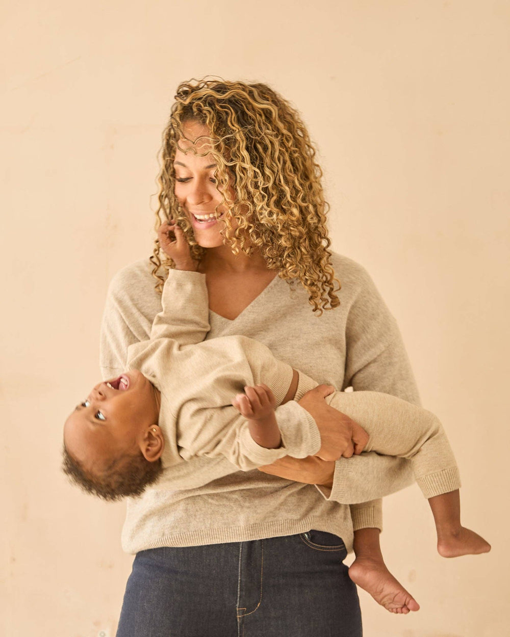 Woman holding a baby against a beige background
