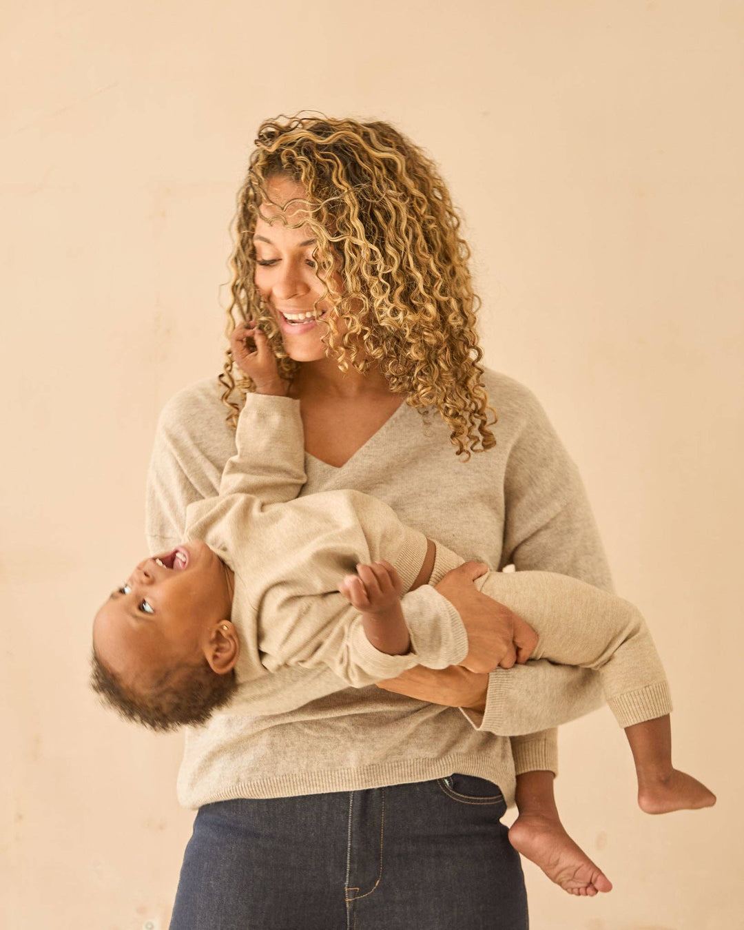 Woman holding a baby against a beige background