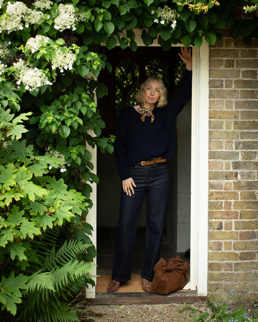 Woman standing in a doorway surrounded by greenery and flowers