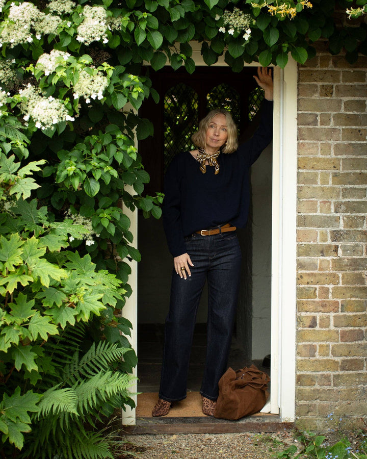 Woman standing in a doorway surrounded by greenery and flowers