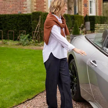 Woman opening a car door in a garden setting