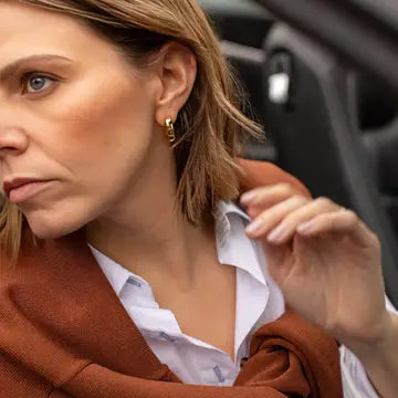 Woman adjusting her collar with a blurred car interior background