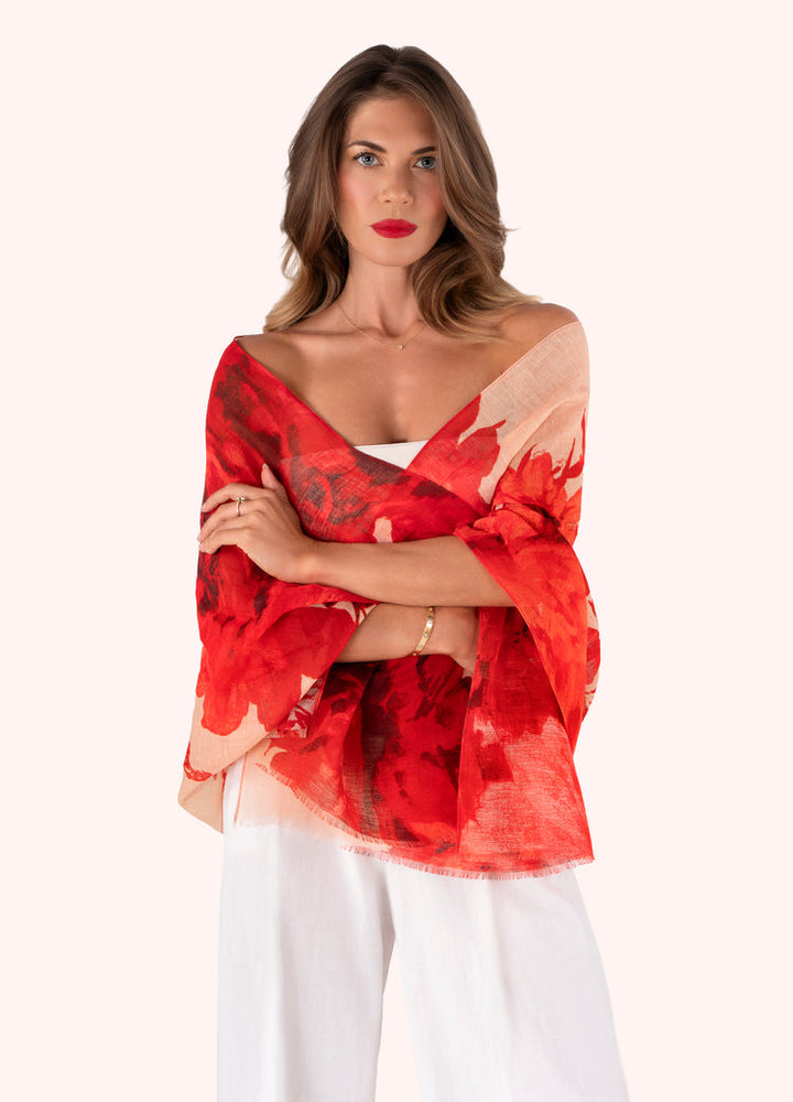 Woman wearing a red and black patterned top with white pants on a white background