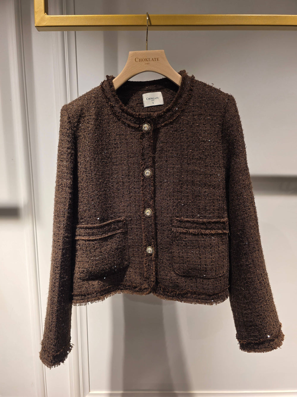 Brown textured jacket on a hanger against a plain background
