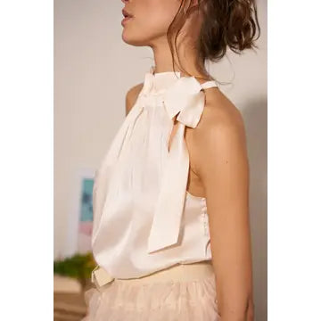 Woman wearing a white blouse with bow details in an indoor setting