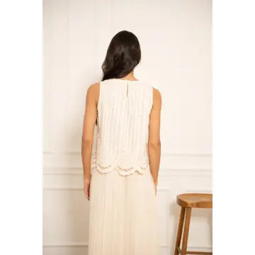 Woman wearing a white sleeveless dress against a plain background