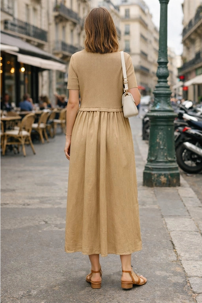 Woman in a beige dress walking down a city street.