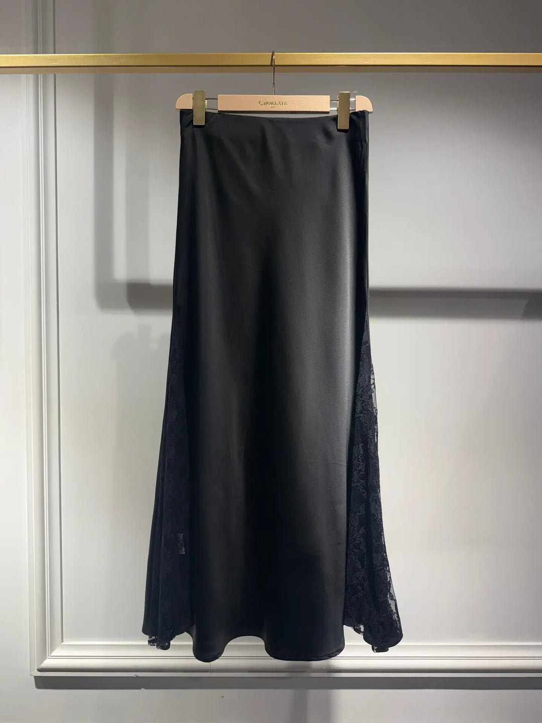 Black skirt hanging on a rack with a neutral background