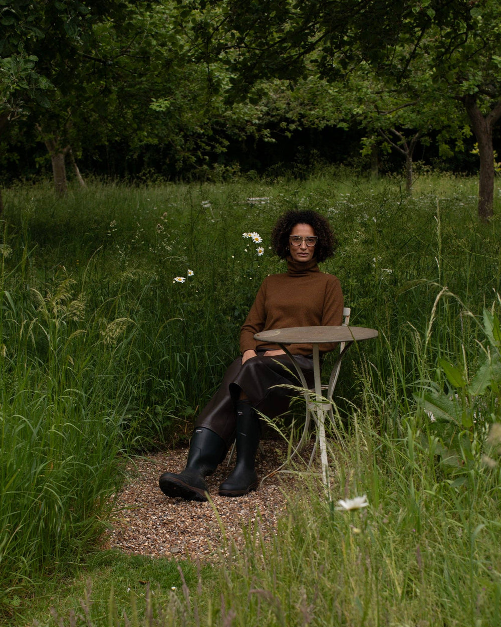 Person sitting at a small table in a grassy outdoor setting