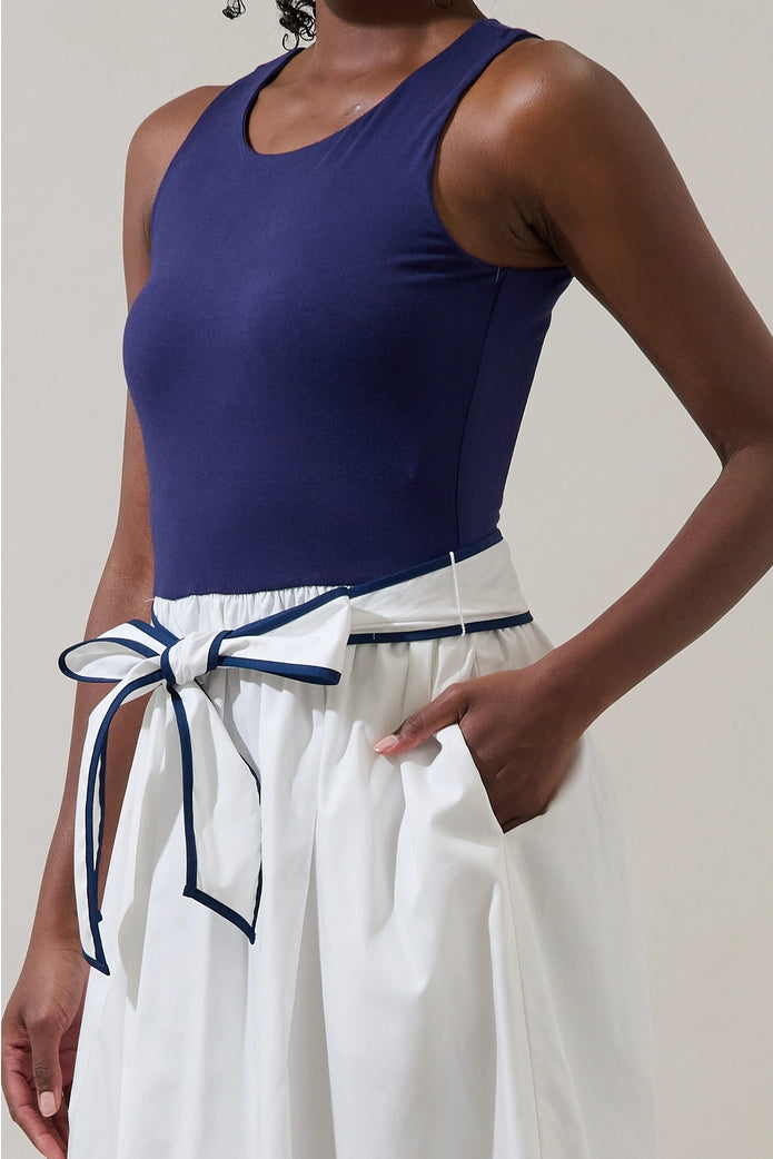 Person wearing a blue tank top and white pants with a blue belt.