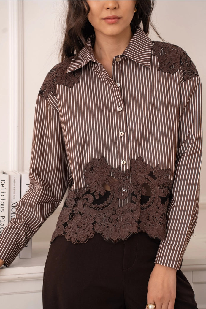 Woman wearing a striped shirt with lace details in a neutral setting