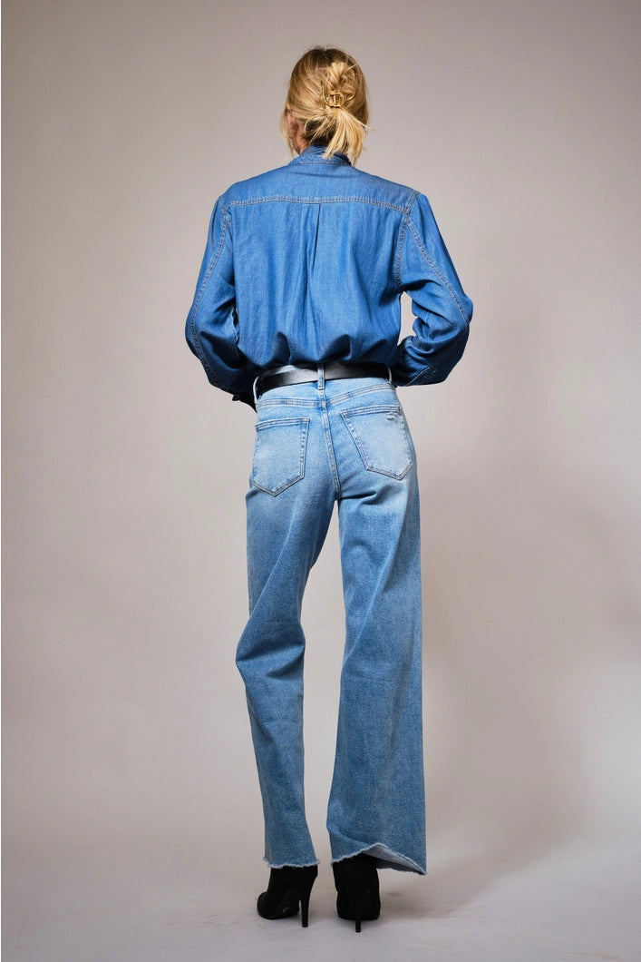 Person wearing a blue denim shirt and jeans on a plain background