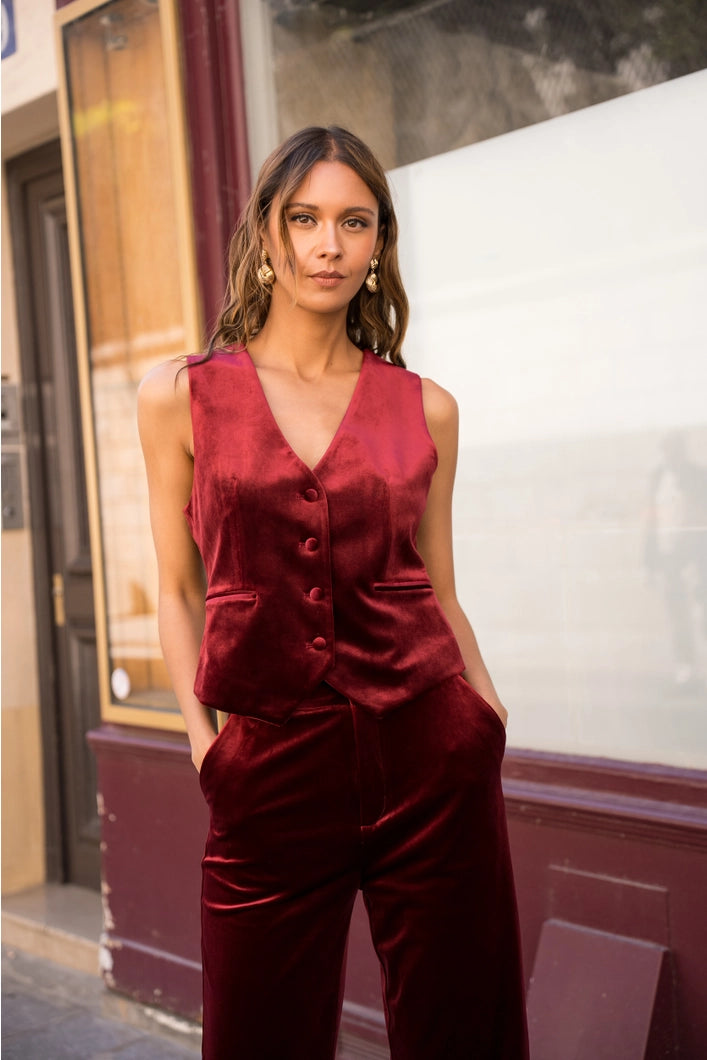 Woman wearing a red satin jumpsuit standing on a street.