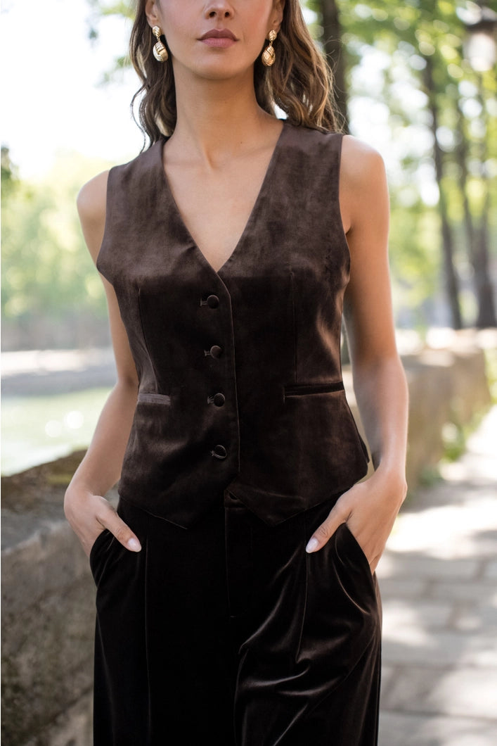 Woman wearing a dark brown sleeveless top and pants outdoors.