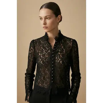 Woman wearing a black lace blouse against a beige background