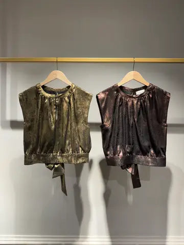 Two  tops hanging on a rack against a neutral background