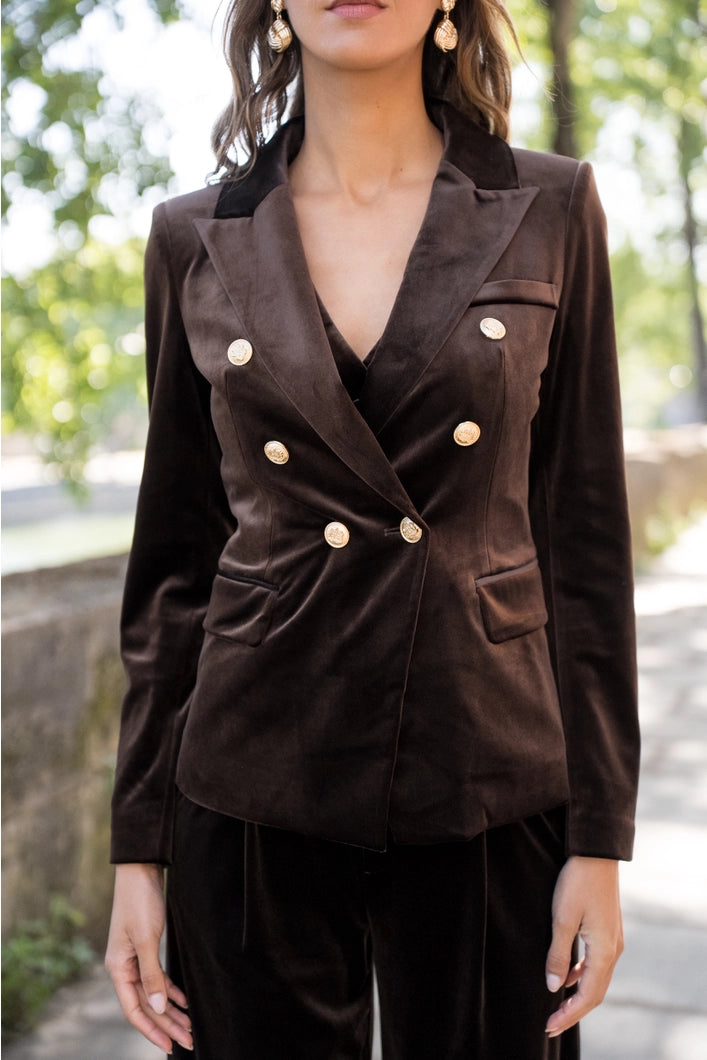 Woman wearing a brown blazer with gold buttons outdoors