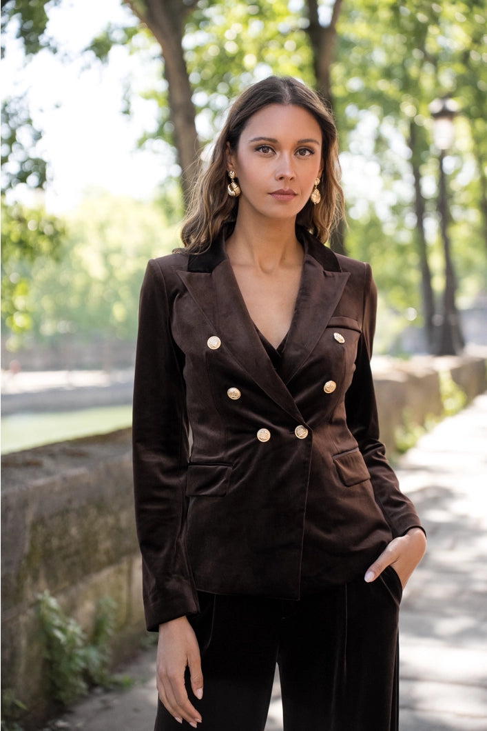 Woman wearing a brown blazer with gold buttons outdoors