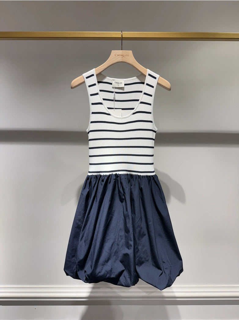 Striped dress with a navy skirt on a hanger against a neutral background