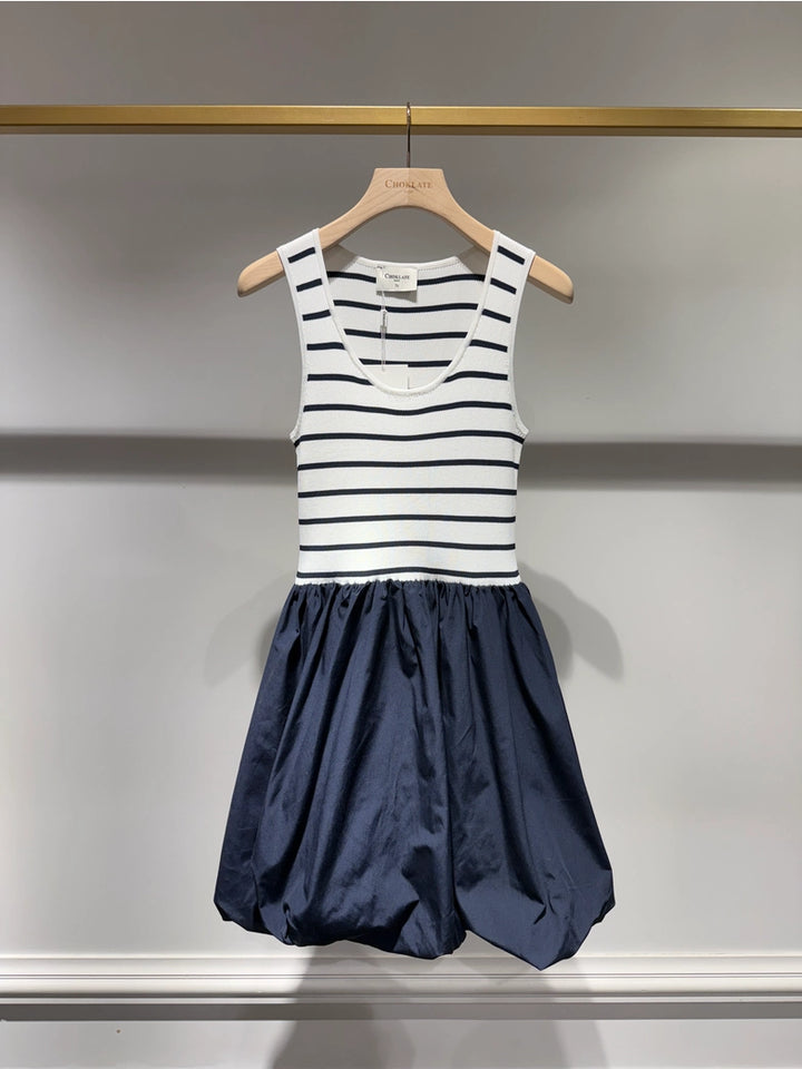Striped dress with a navy skirt on a hanger against a neutral background