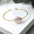 Gold bracelet with a pink gemstone on a white surface