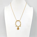 Gold necklace with a circular pendant on a white background