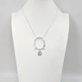 Silver necklace with a circular pendant on a white background