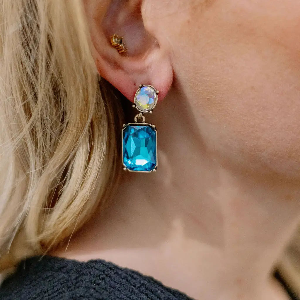 Close-up of a person wearing a blue gemstone earring with a blurred background