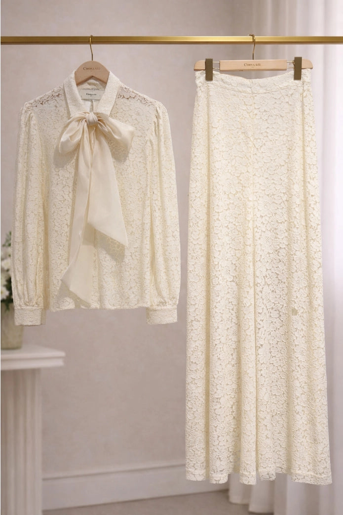 Lace blouse and pants set hanging on a rack against a neutral background