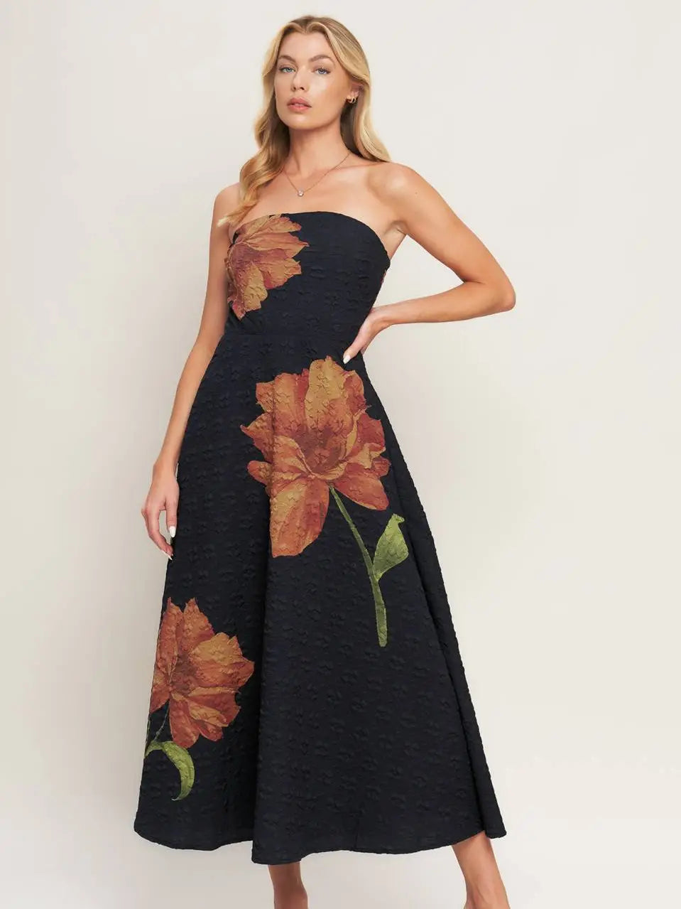 Woman wearing a black strapless dress with floral patterns on a white background