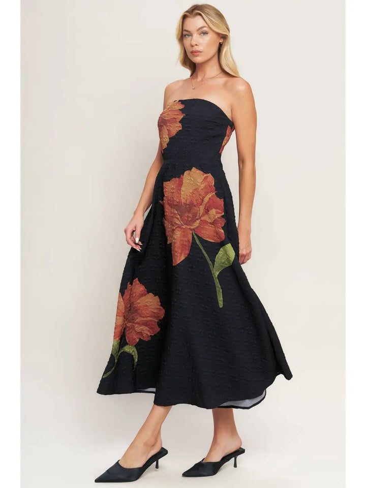 Woman wearing a black strapless dress with floral patterns on a white background