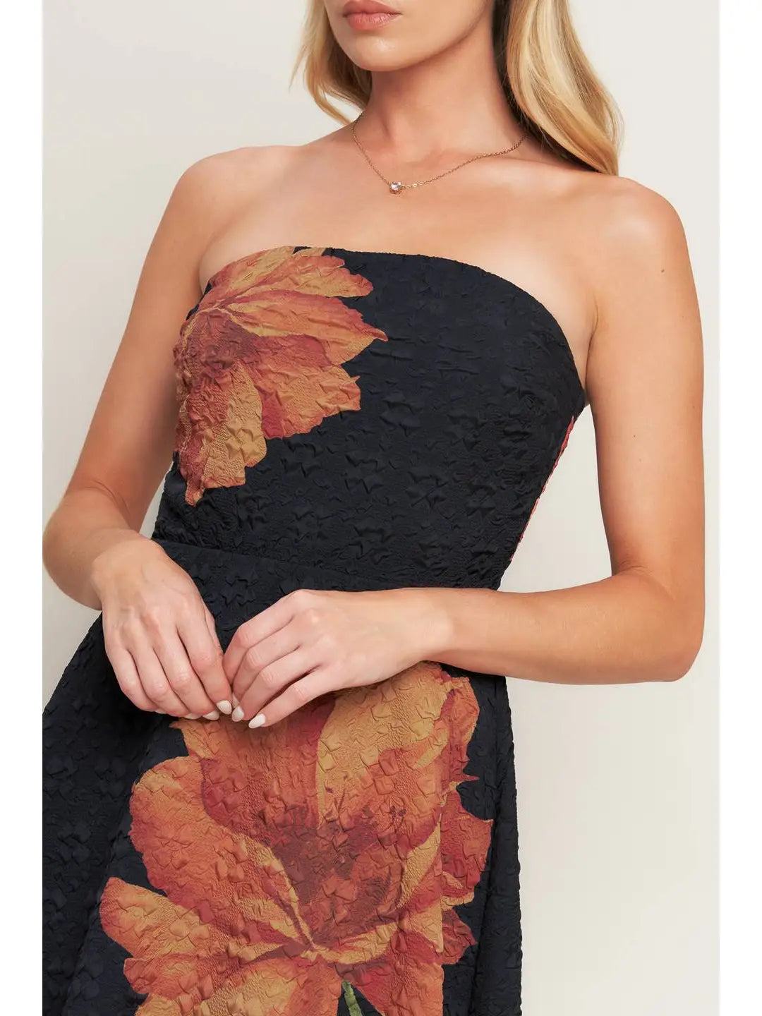 Woman wearing a strapless dress with floral patterns on a plain background