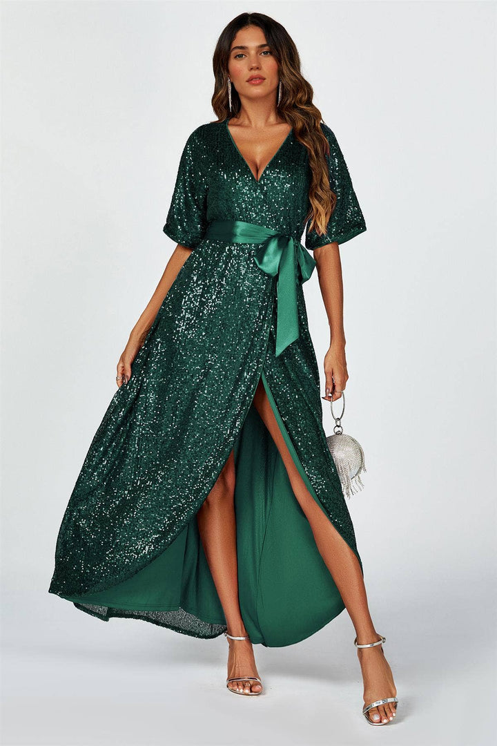 Woman wearing a green sequin dress with a slit on a white background