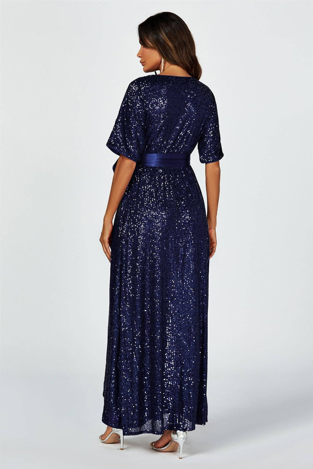 Woman wearing a long navy blue sequin dress on a white background