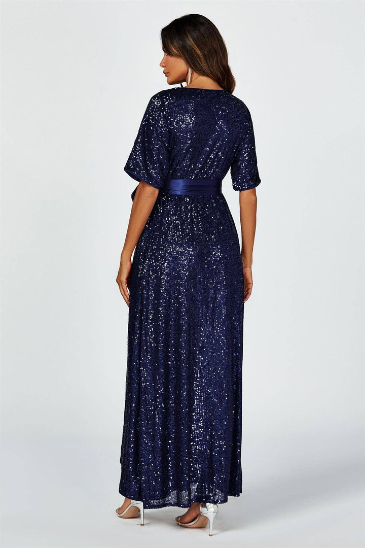 Woman wearing a long navy blue sequin dress on a white background